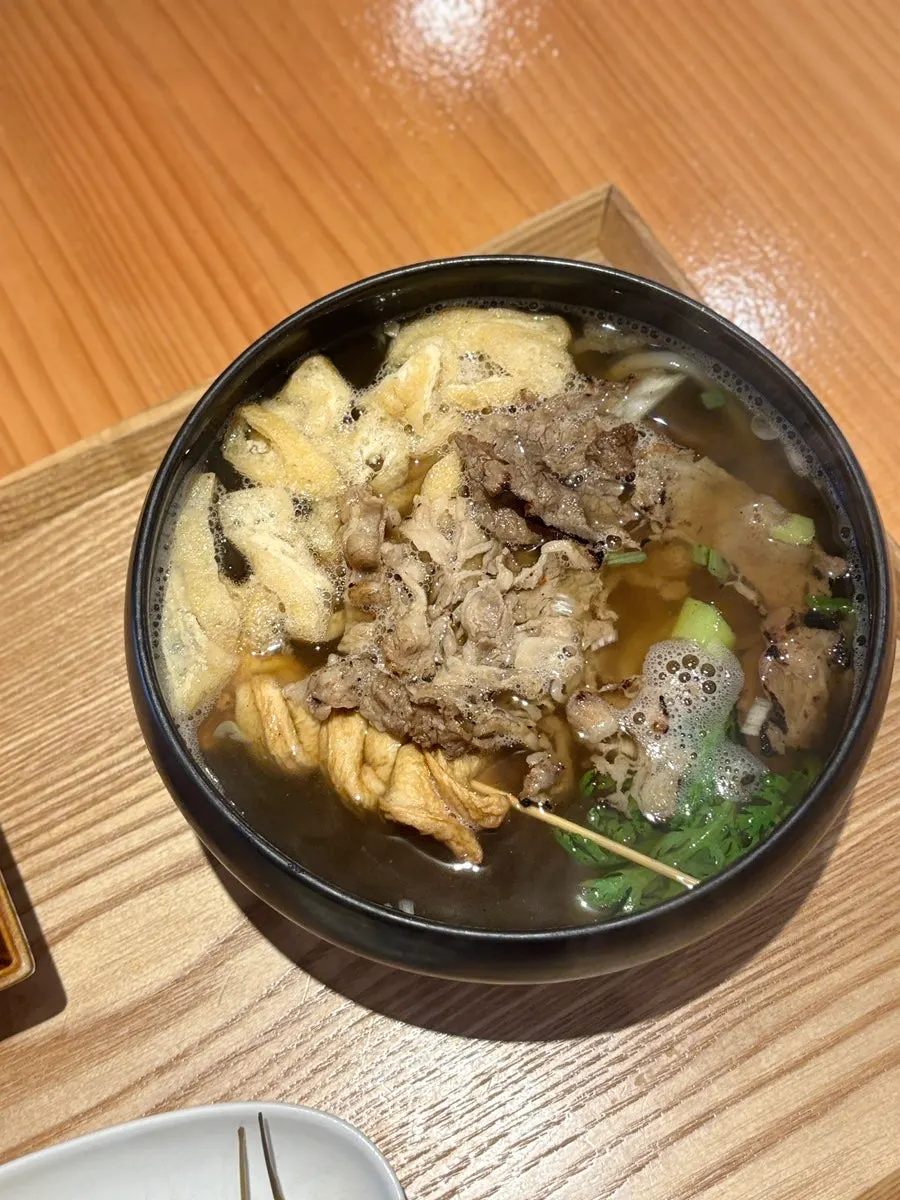 Udon topped with fish cake, fried tofu, and beef brisket