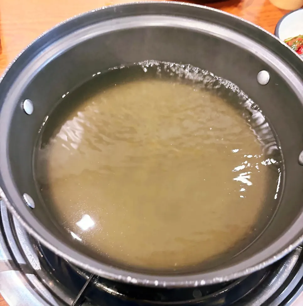 Kalguksu noodles boiling in clear seafood broth