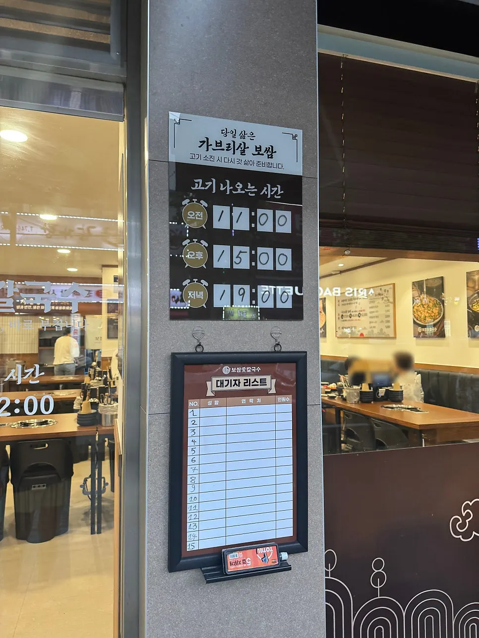 Papan maklumat masa daging dihidangkan dan papan beratur di depan kedai