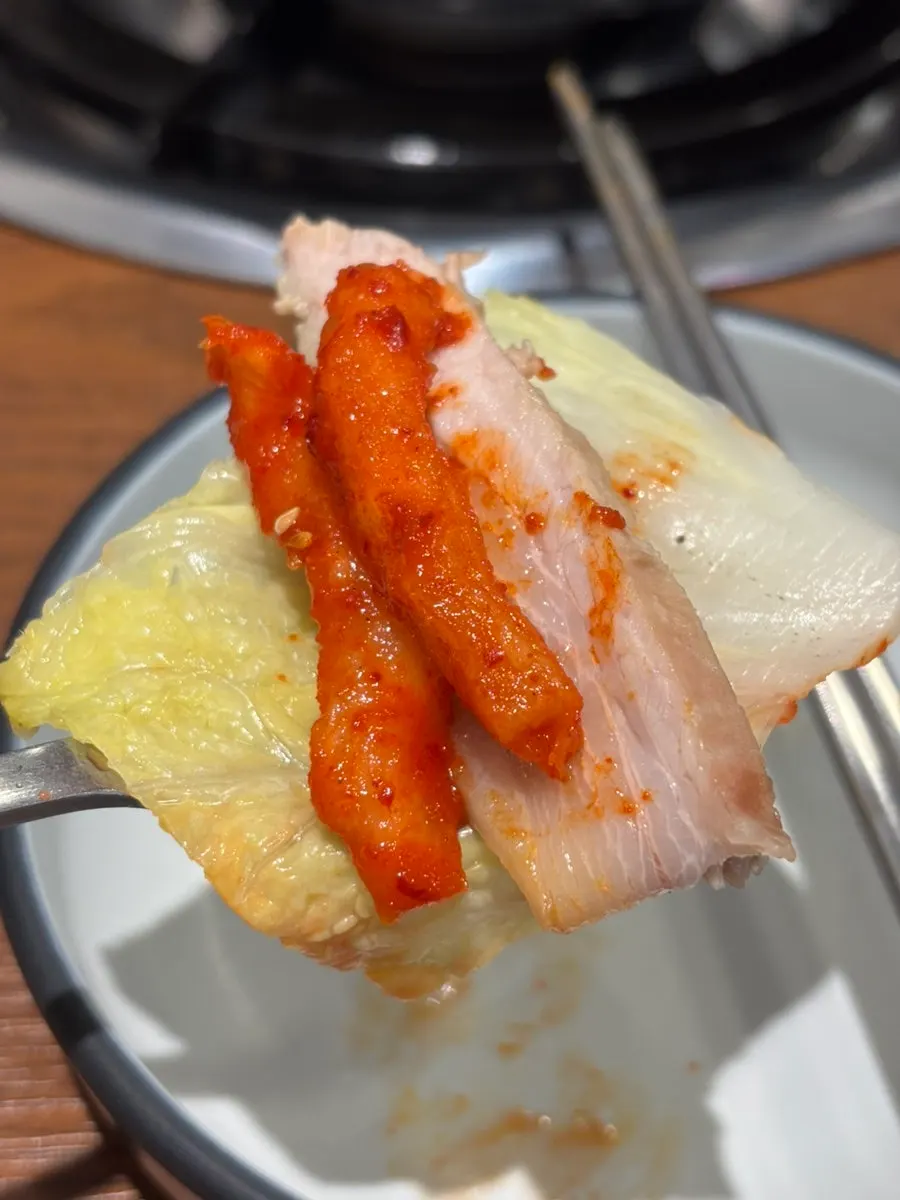 A bossam wrap topped with ssamjang and salted shrimp