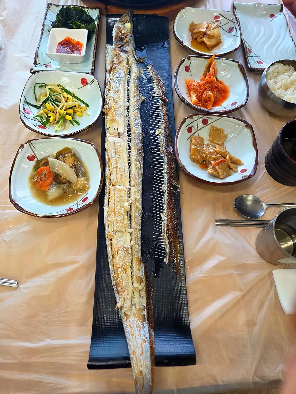 Whole grilled cutlassfish prepared by a staff member