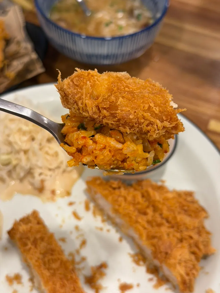 A spoonful of pork rice bowl topped with pork cutlet