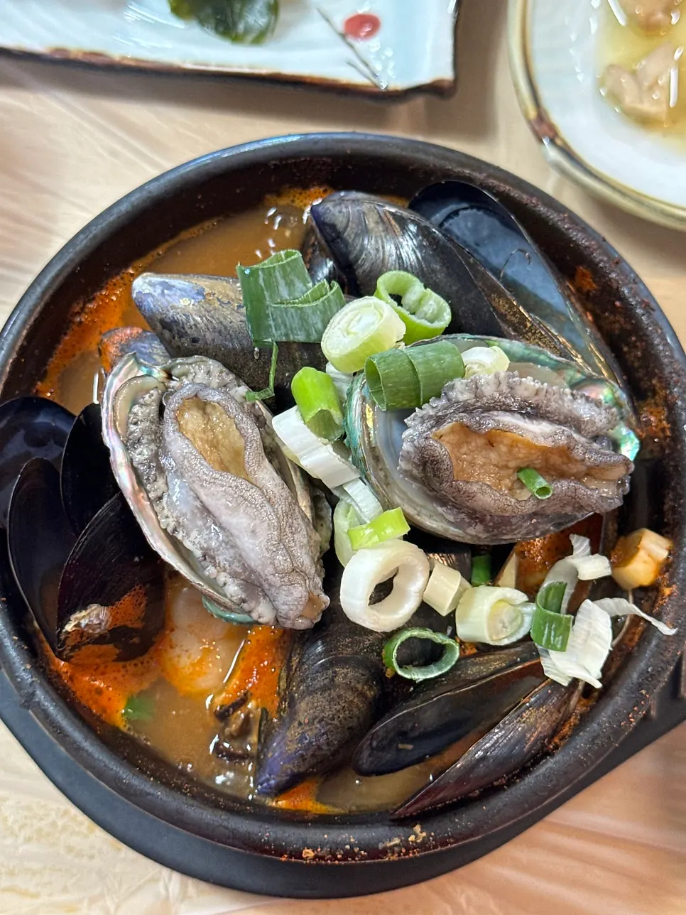 Spoonful of seafood stew broth being scooped up