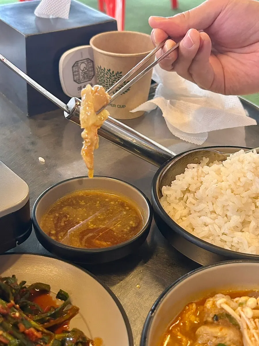 A ladleful of the rich tendon hot pot broth