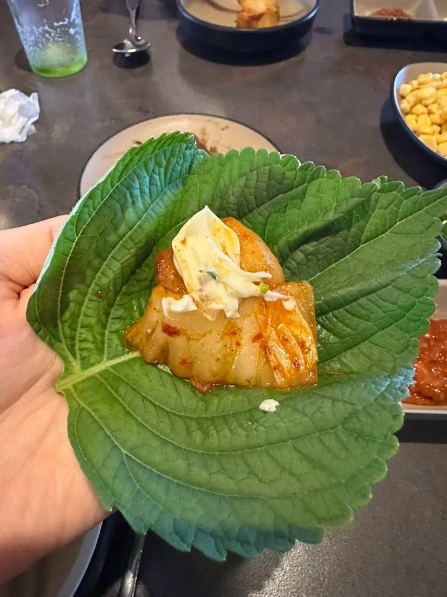 A bite of pork belly wrapped in kimchi