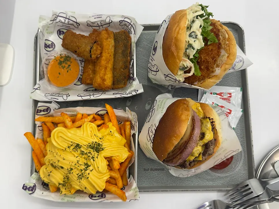 Two burgers with eggplant fritters and butter garlic fries table setting