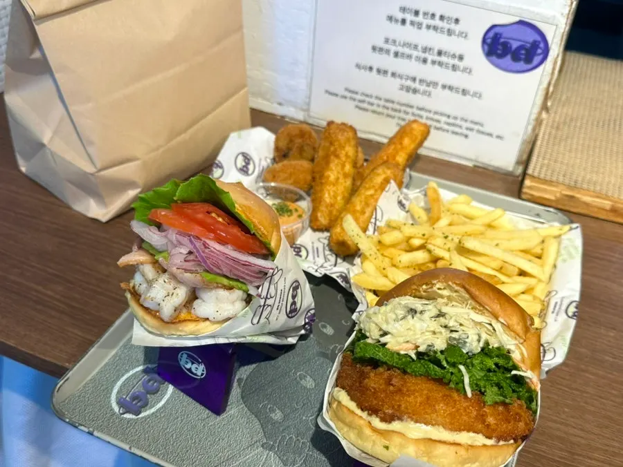 Picked-up spread of burgers and fritter sides