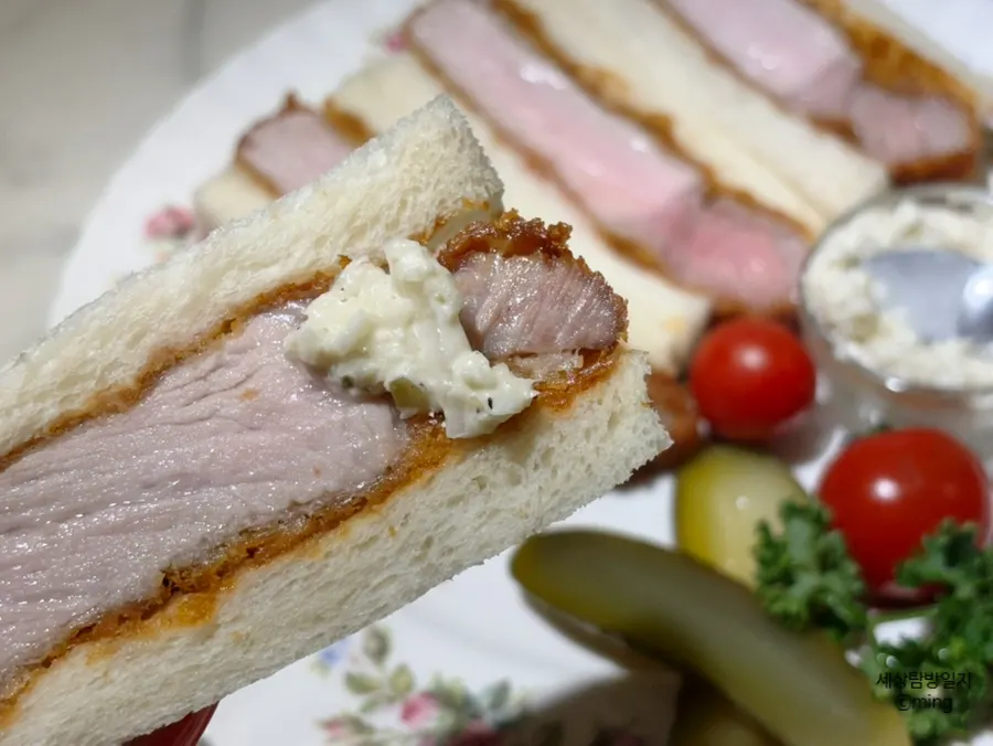 Katsu sando dipped in sauce alongside pickles