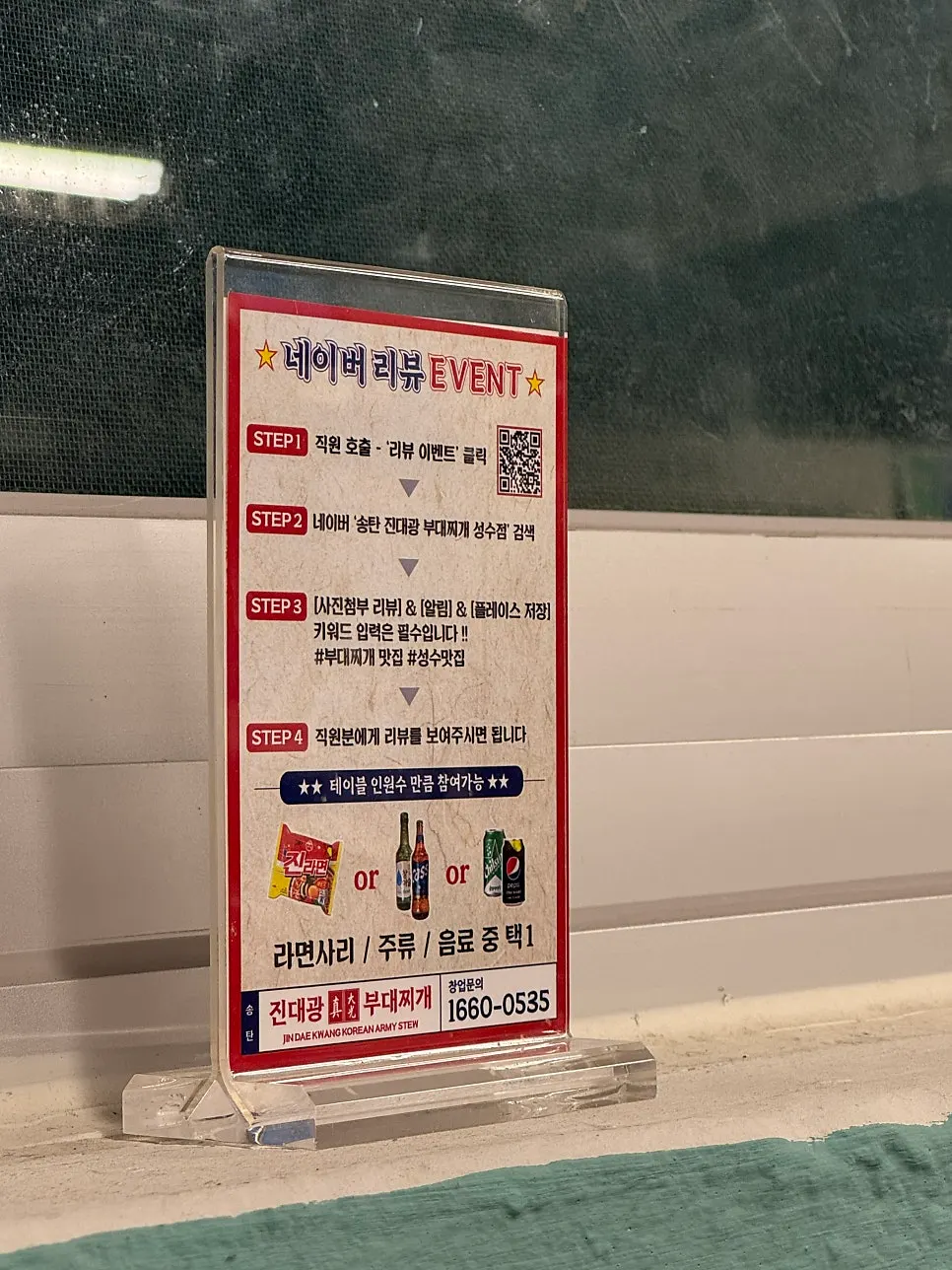 Menu board listing budae jjigae, noodle add-ons, and drinks