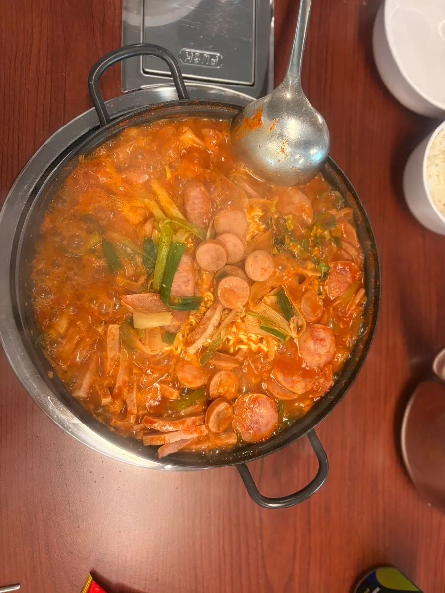 Mesa servida con budae jjigae y arroz