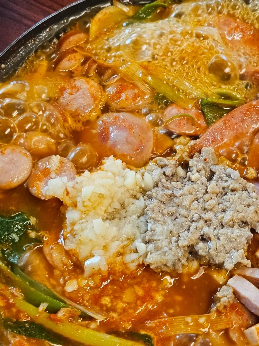 밥에 국물과 소시지를 올린 한 술