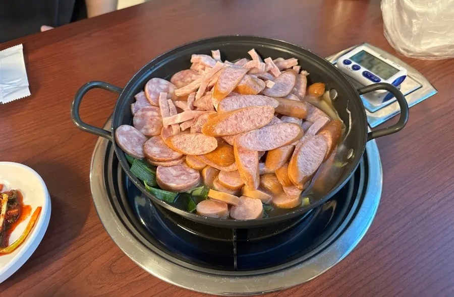A pot of budae jjigae piled high with ham