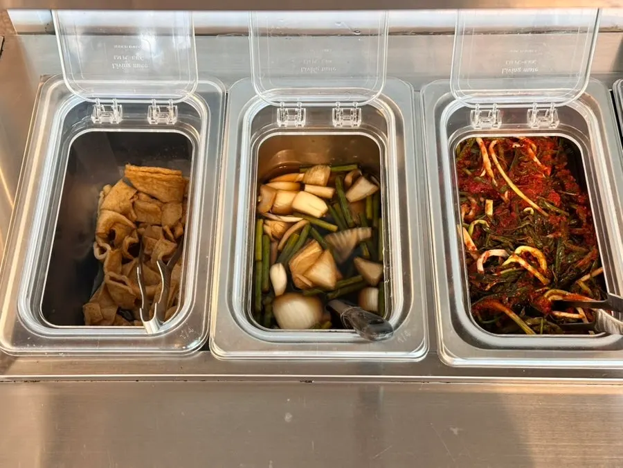 Self-serve side dish corner with pickled onions and green onion kimchi