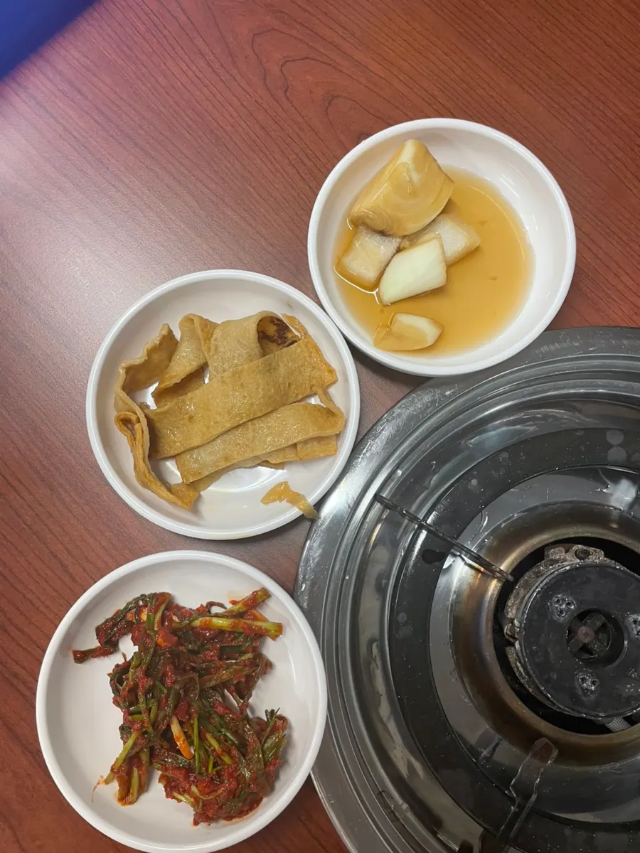 Table set with three side dishes: stir-fried fish cake, pickled onion, and seasoned scallions