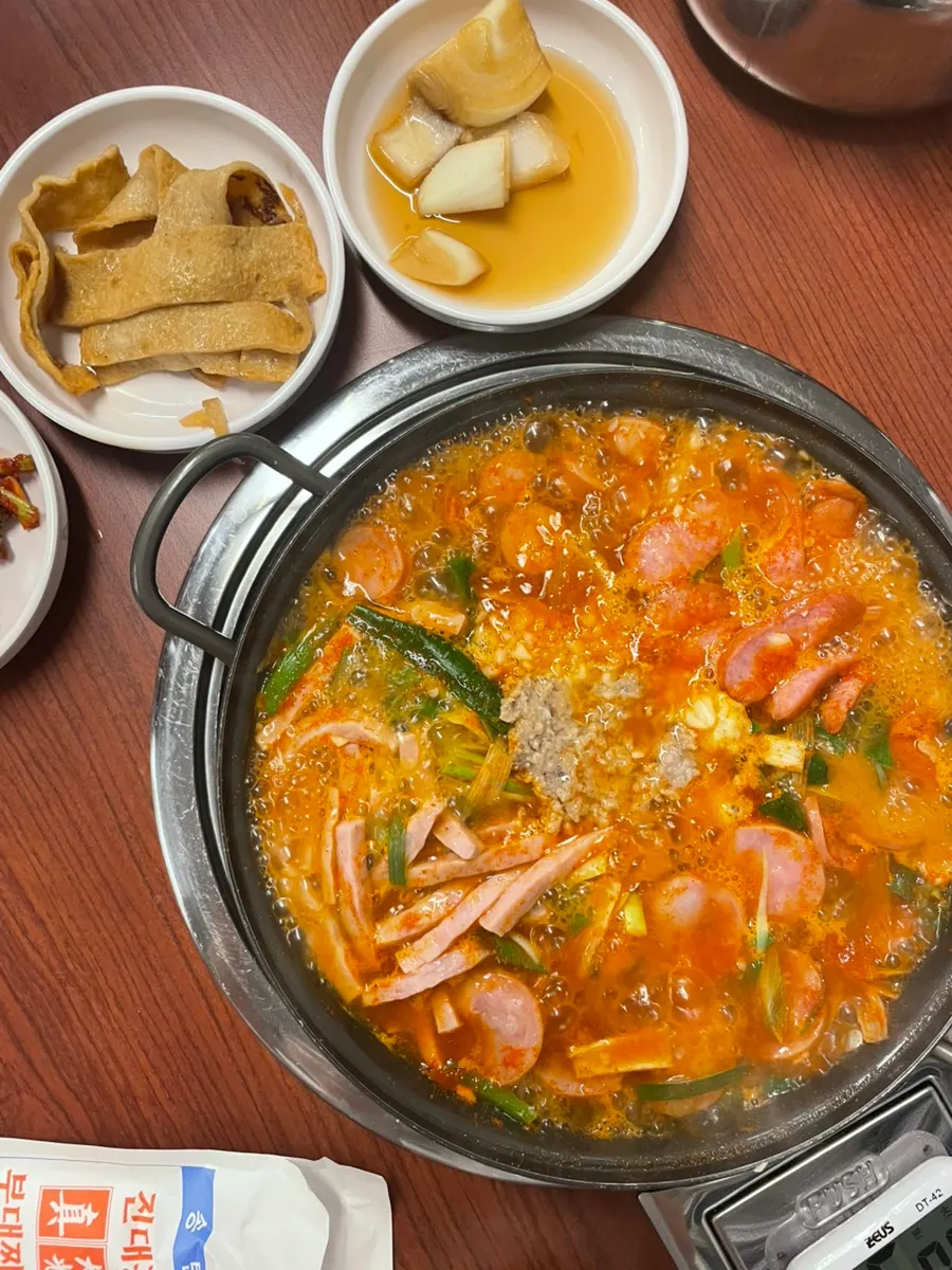 Lid lifted off the pot to reveal a stew packed with sausages