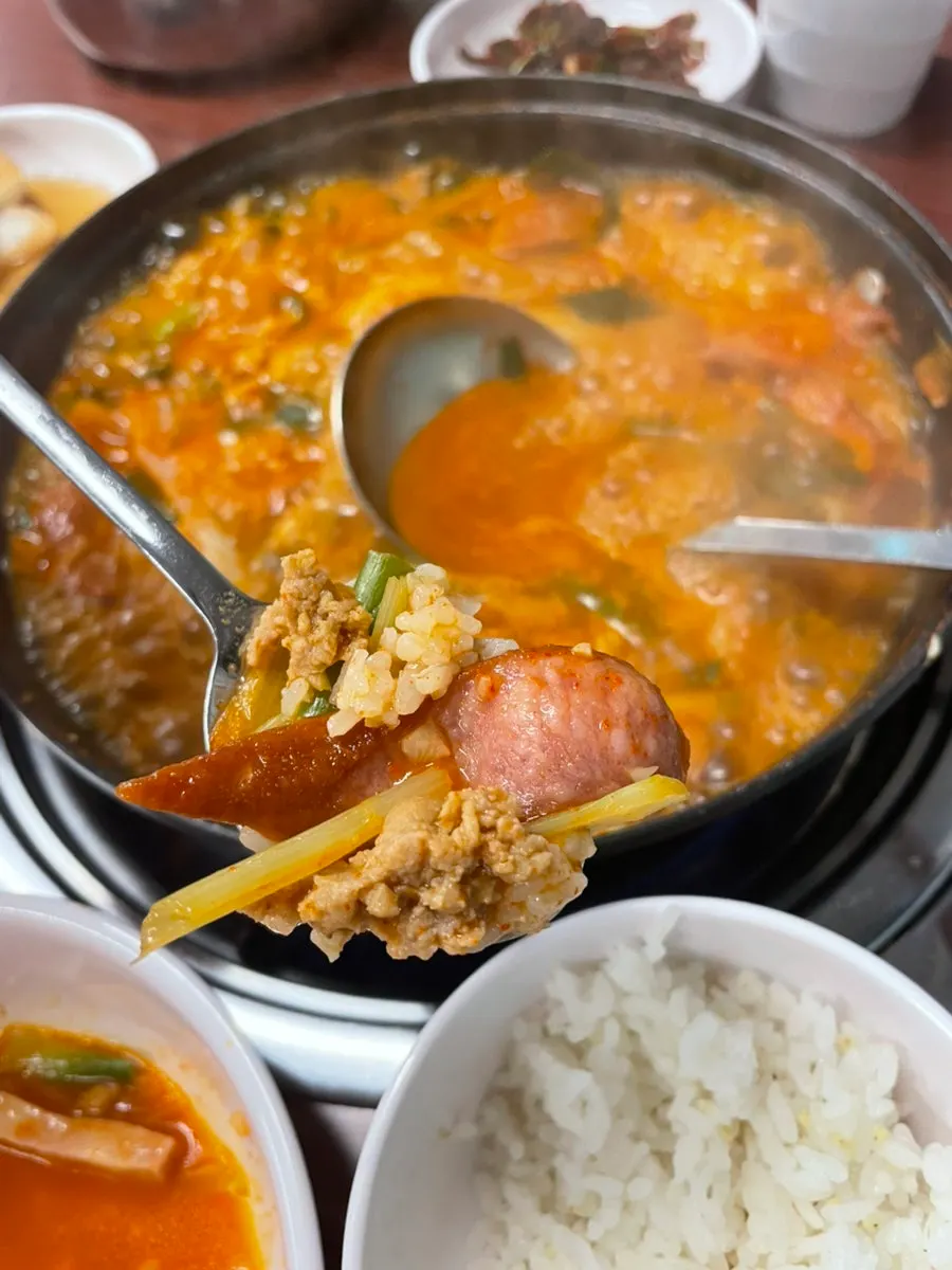 A ladleful of stew scooped up with sausage