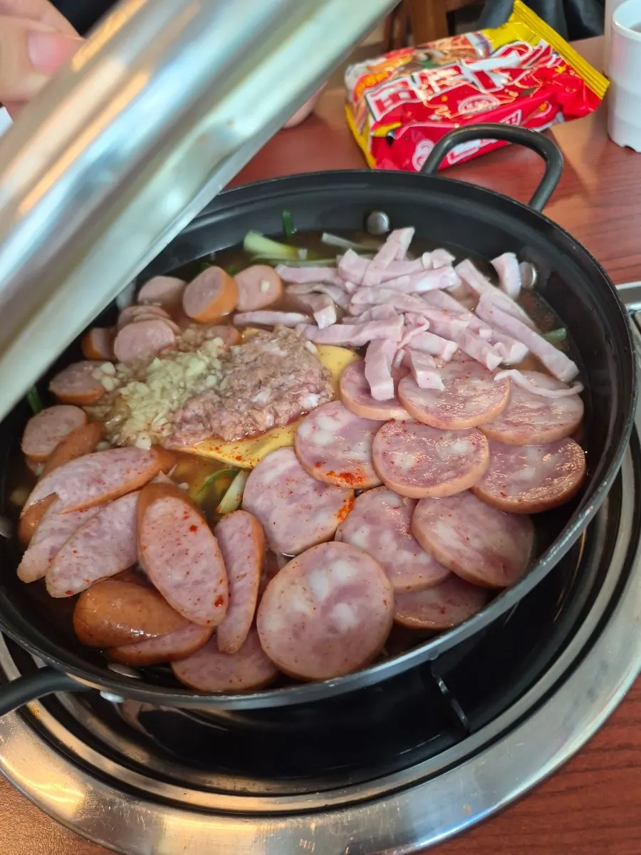 Pot of budae jjigae filled with ham and sausage
