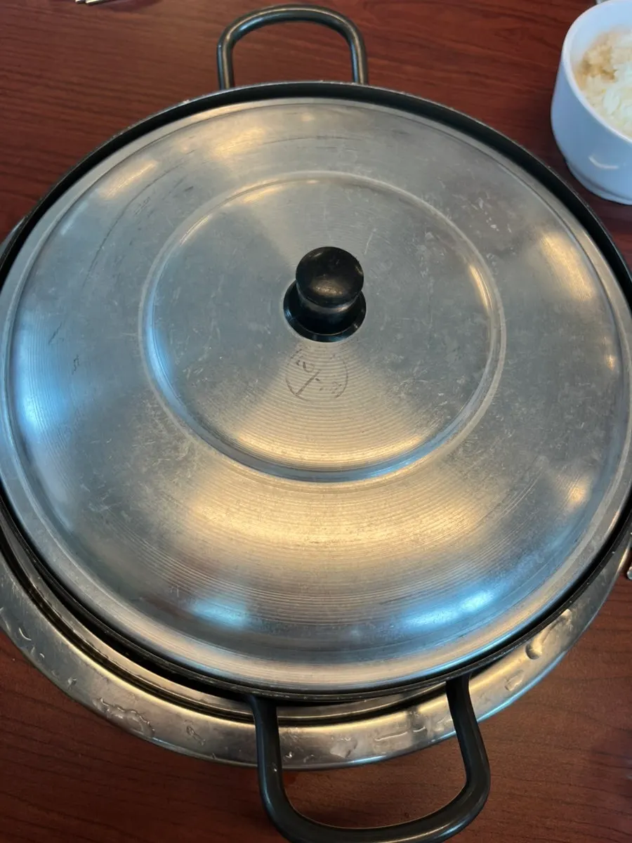 Budae jjigae pot with lid on the tabletop burner