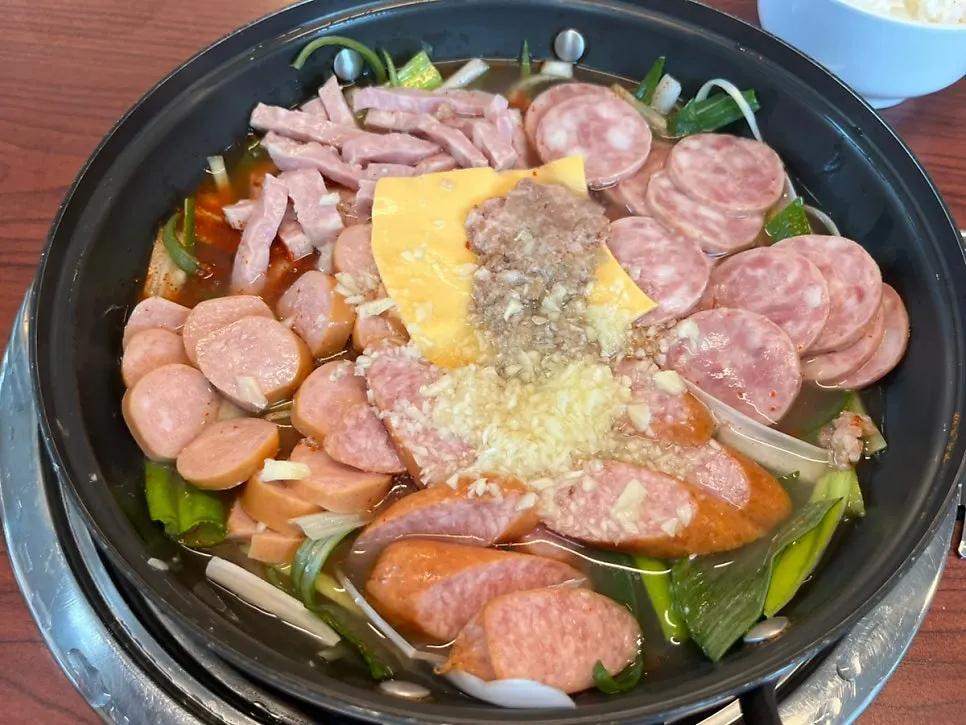 Budae jjigae topped with sausage, Spam, and cheddar cheese