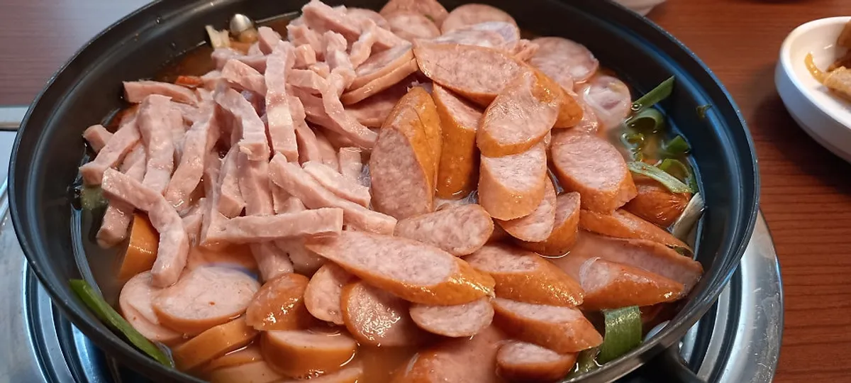 Budae jjigae pot filled with ham and assorted sausages