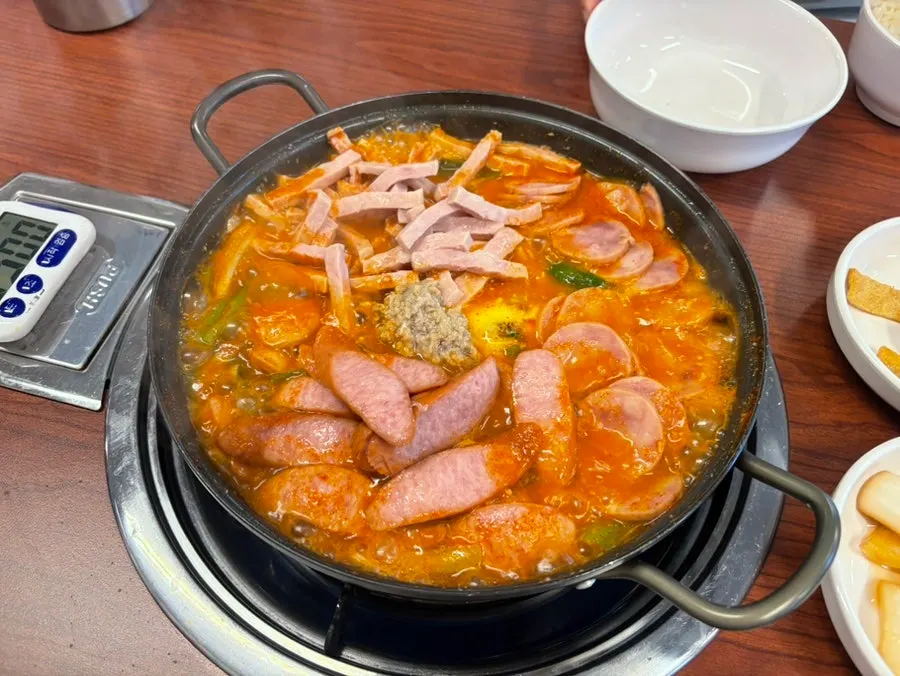 Budae jjigae with its lid opened after timer cooking