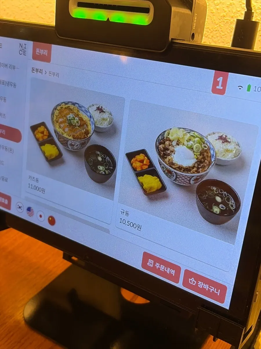 Signboard listing hot udon and rice bowl menu