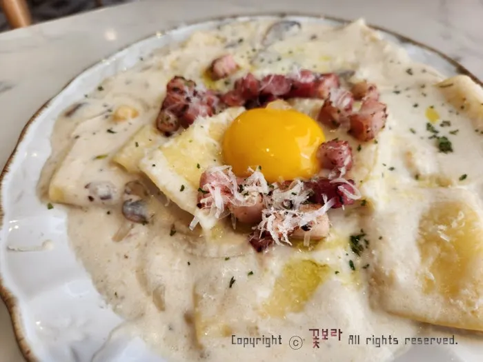 A plate of flat carbonara topped with egg yolk