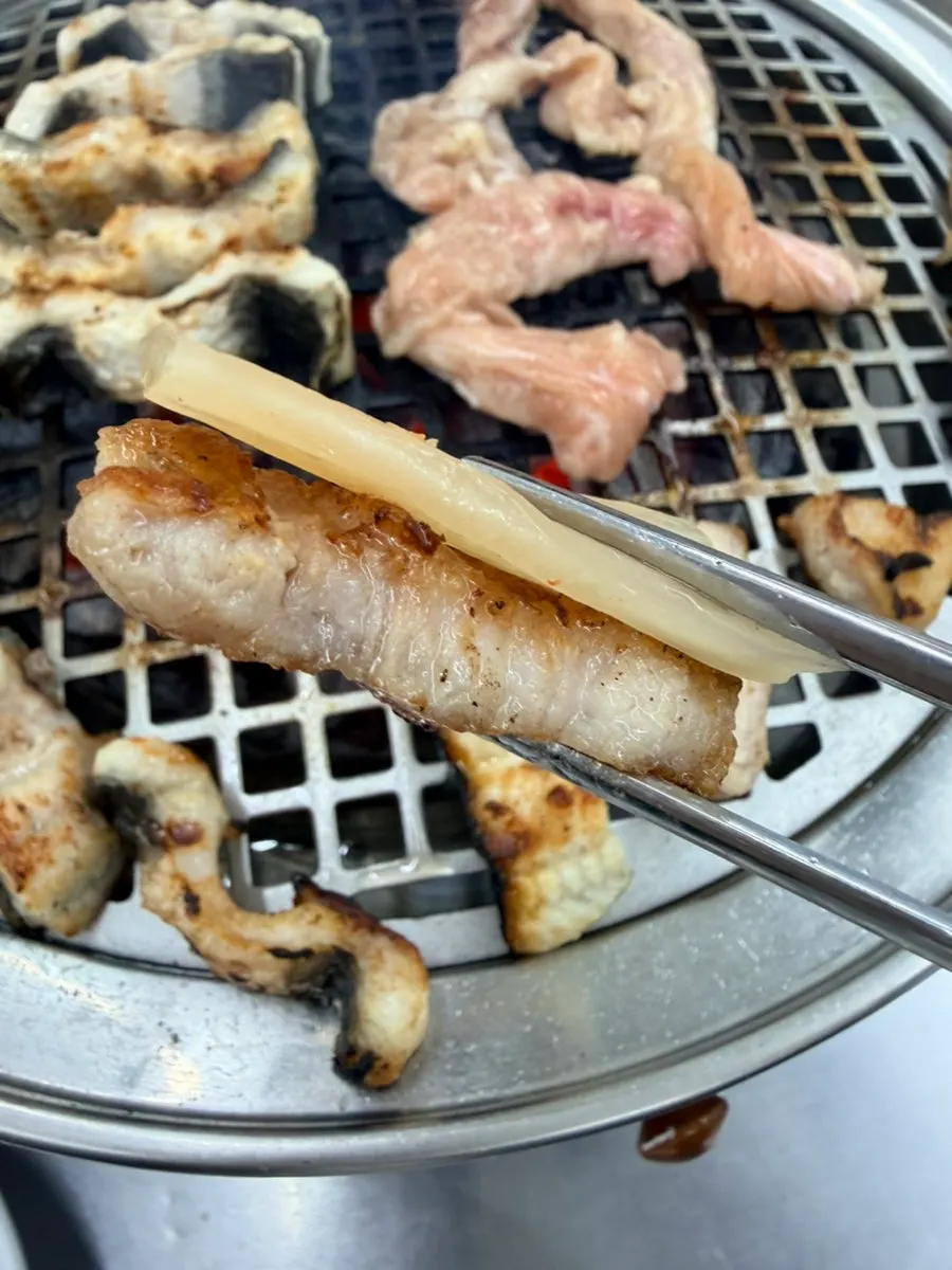 A bite of eel topped with green onion kimchi