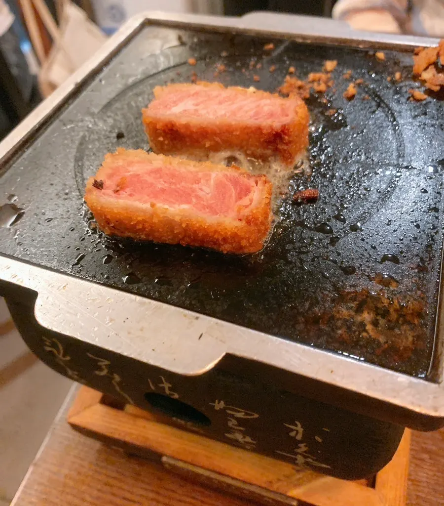 Butter placed between two pieces of gyukatsu on the brazier
