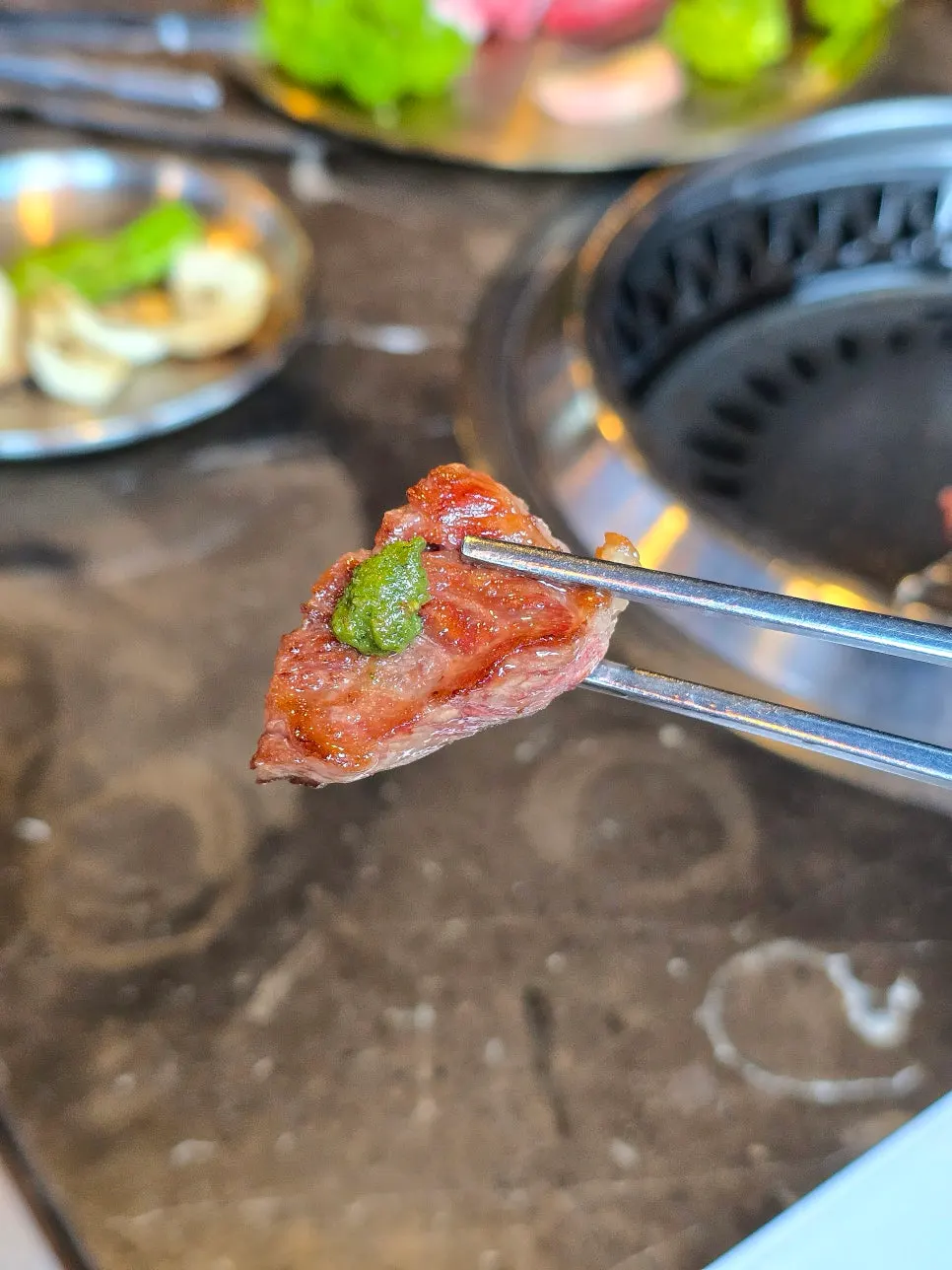 A bite of Marblejeong's grilled beef with lettuce wrap and sauce