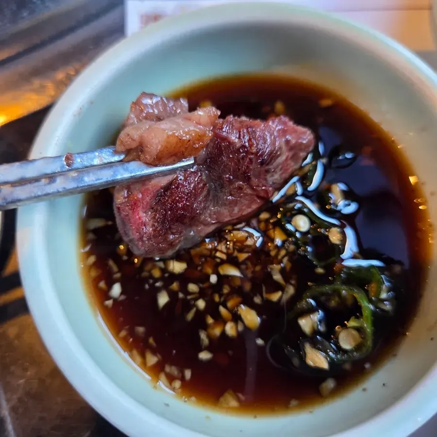 A piece of sirloin dipped in soy sauce sauce