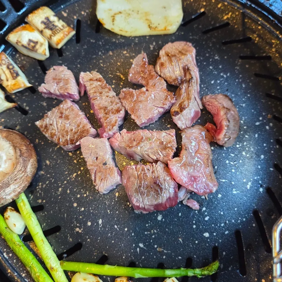 Brisket point grilling alongside garlic