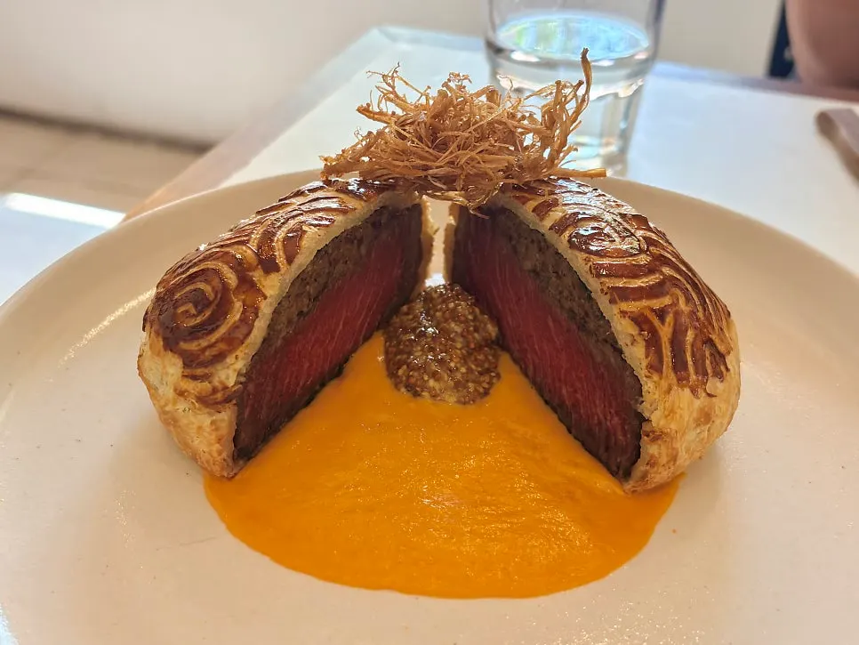 Side-angle shot of beef Wellington with corn puree