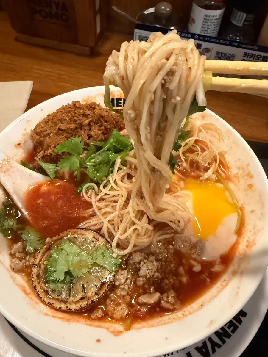 Tom yum-based ramen broth topped with cilantro