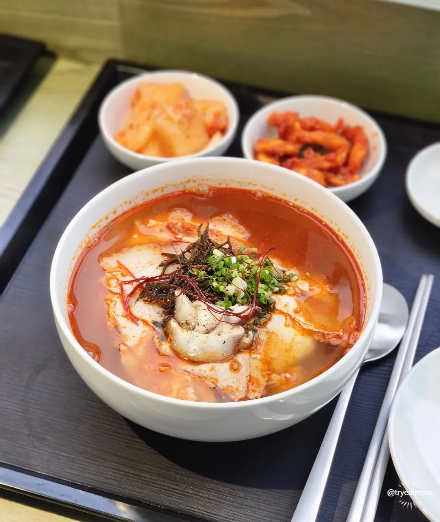 Spoonful of clear gomtang broth lifted from the bowl