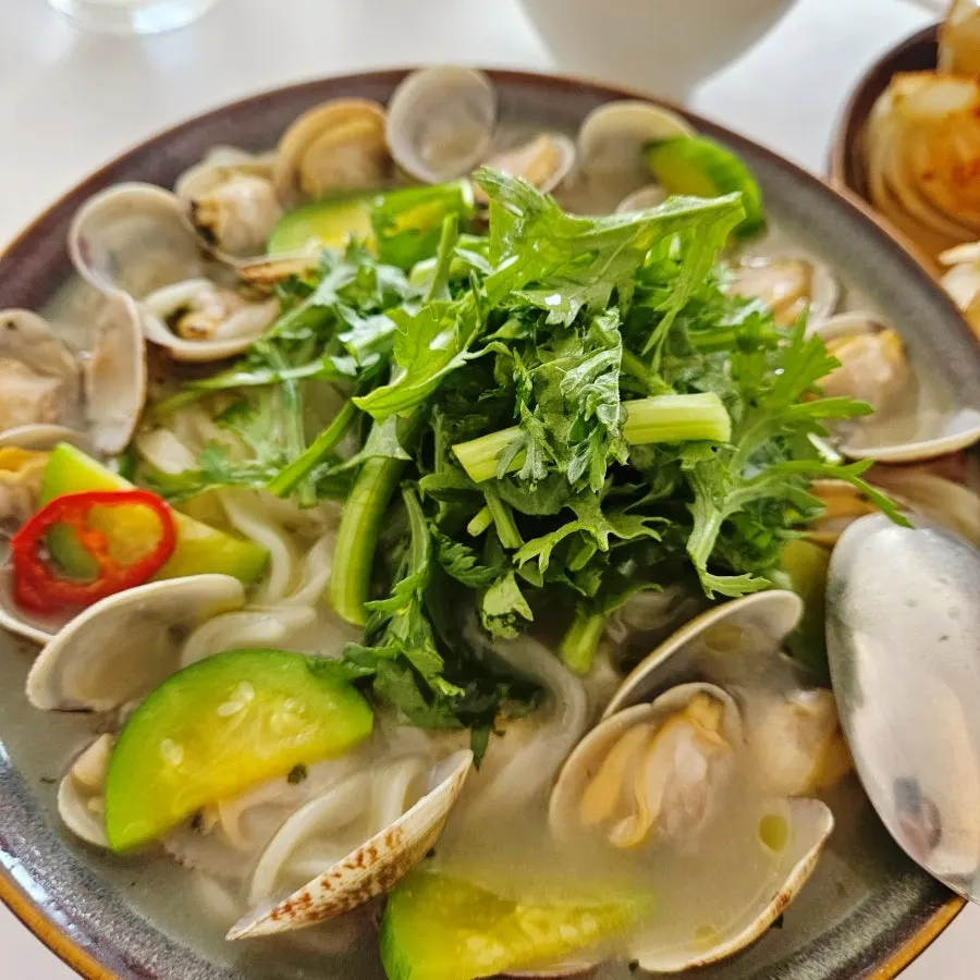 Kalguksu noodles and broth topped with crown daisy
