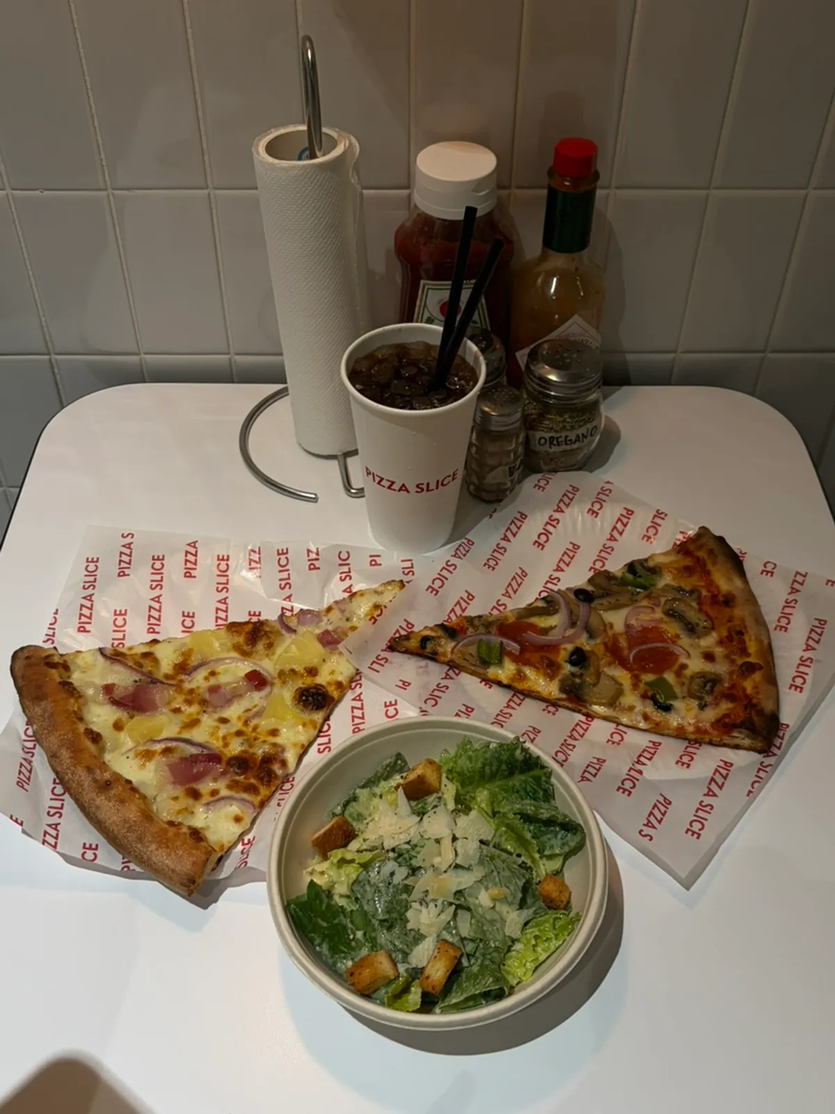Two pizza slices and a Caesar salad on the table
