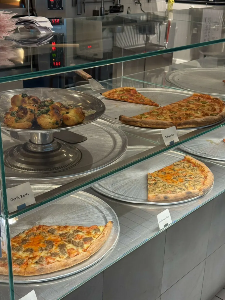 Various pizzas displayed by the slice