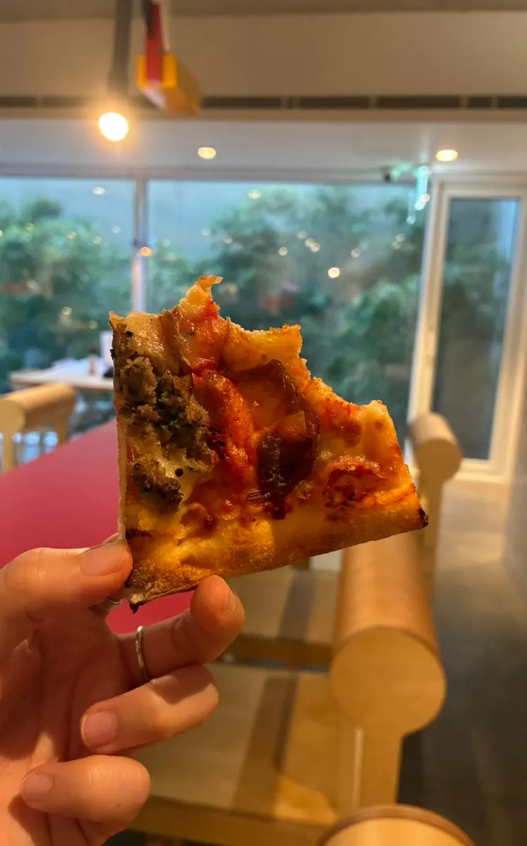 A big pizza slice held in one hand
