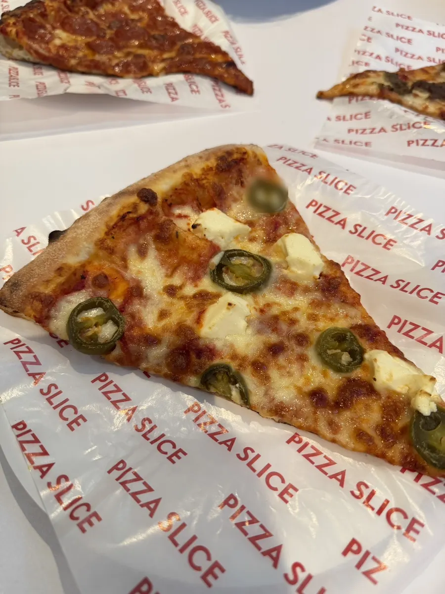 Pizza slice compared in size to an adult woman's fist