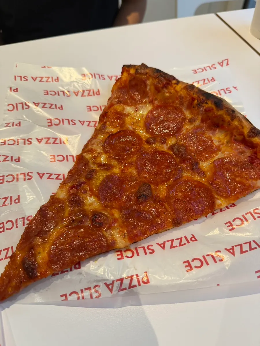 Homemade meatball pizza slice drizzled with hot sauce