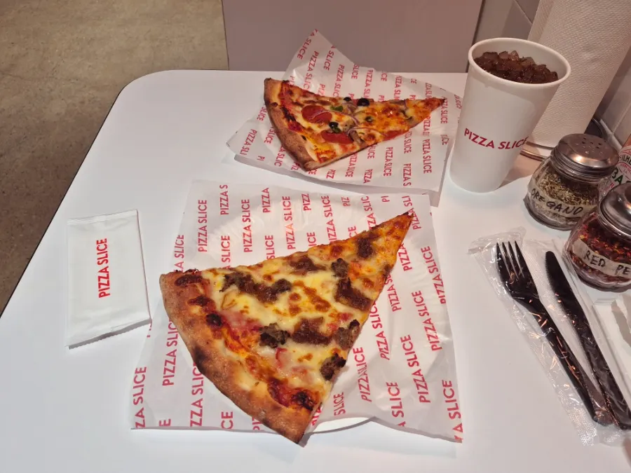 Two pizza slices and a Coke brought to the table