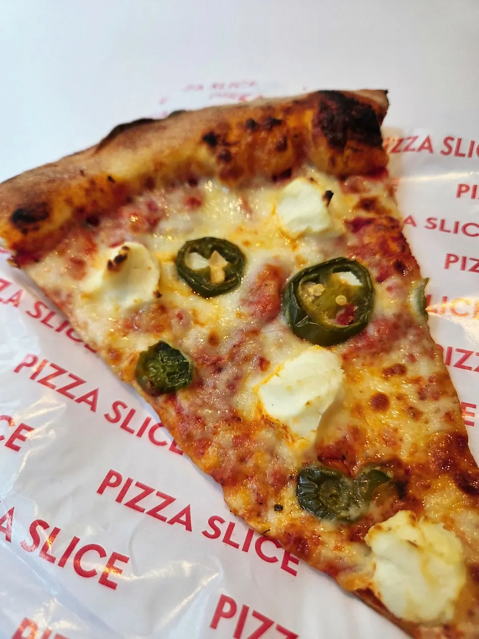 Thin-crust pizza slice held in one hand