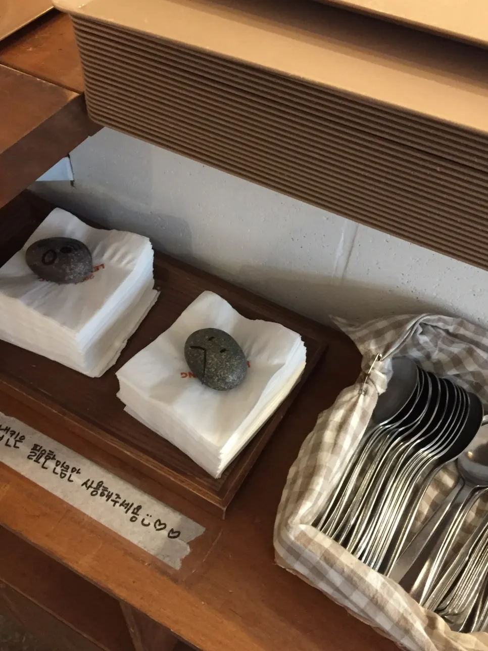 Self-service napkin and spoon corner with a small stone on top