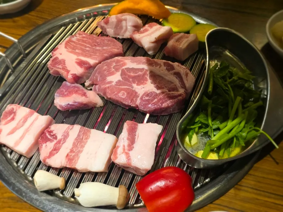 Meat grilling alongside vegetables