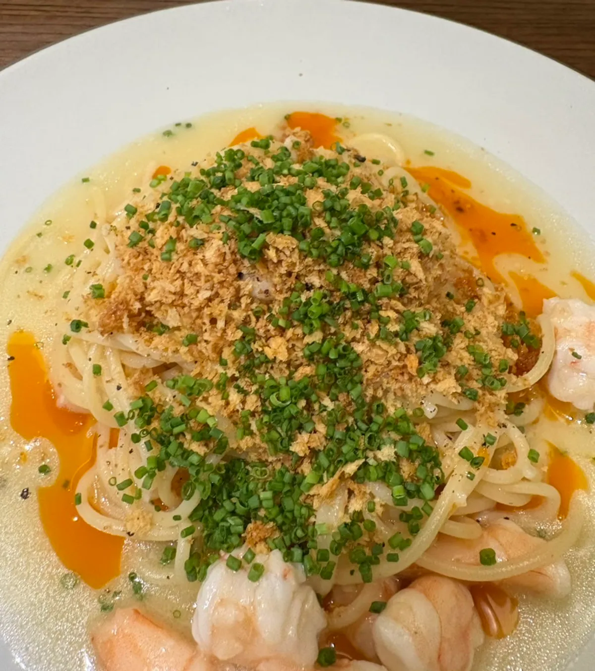 A plate of shrimp pasta topped with chives and crumble