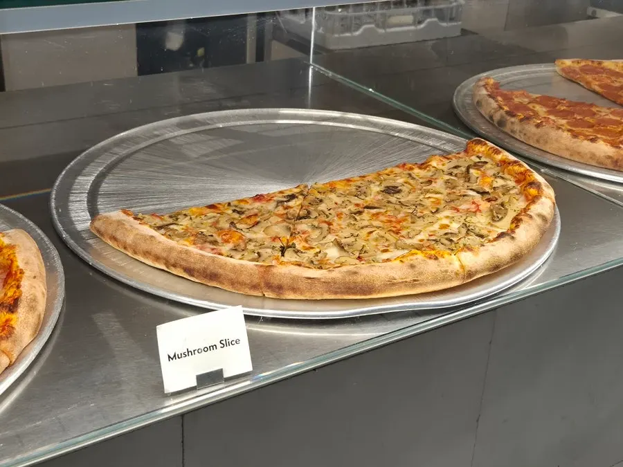 Display case lined with various slice pizza types