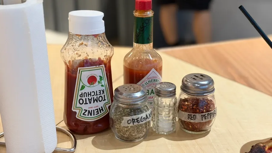 Hot sauce, ketchup, pepper, and salt set out on the table