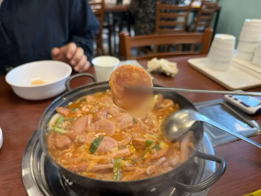 Budae jjigae boiling, full of ham and sausage