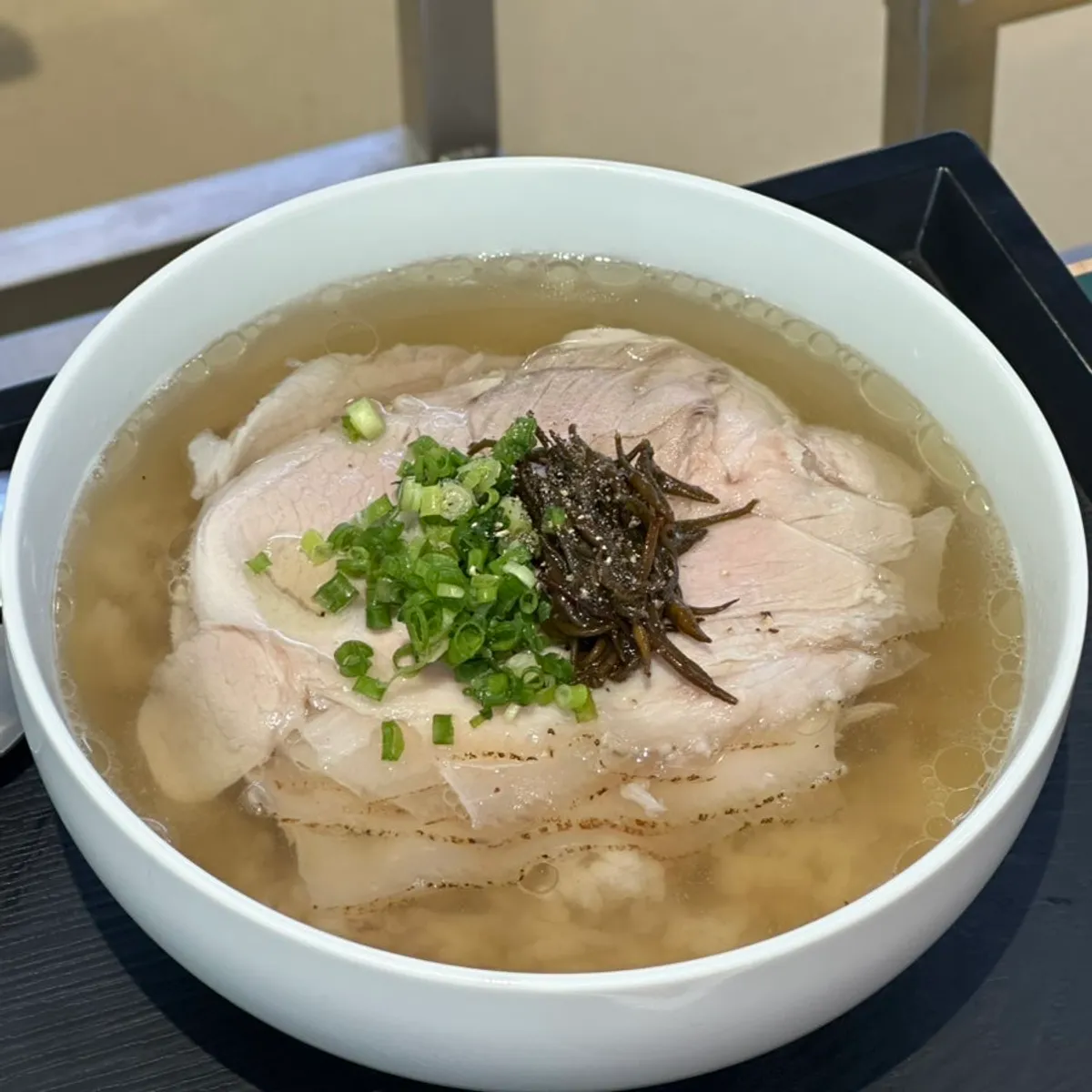 A bowl of clear gomtang topped with pork